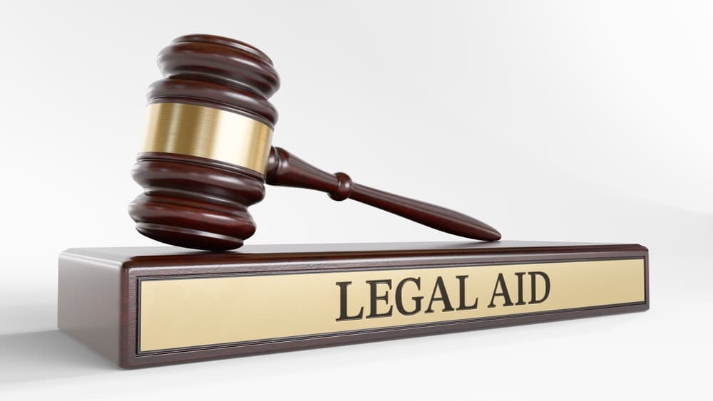Legal Aid: A judge's gavel as a symbol of the legal system, placed on a wooden stand with the word "LEGAL AID."
