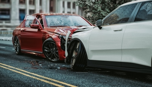 Red car and white SUV with heavy front-end damage after a head-on collision on a city street.