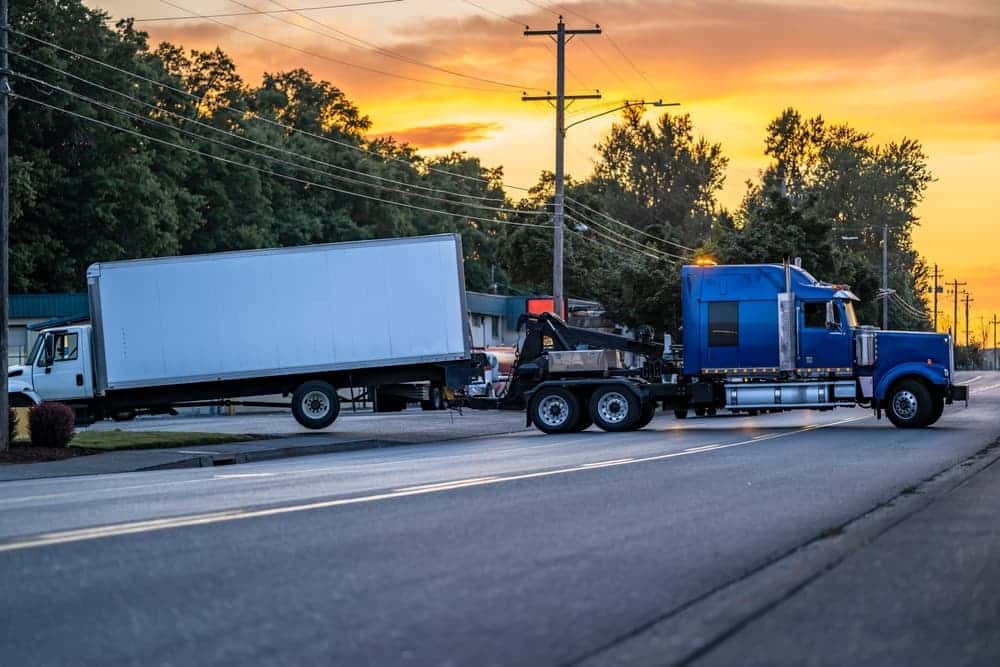 Tow truck assists a damaged semi-truck, highlighting shared liability scenarios in trucking accident cases.