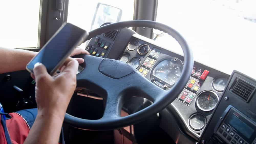 Closeup photo of truck driver using smartphone while driving. Danger in transport. Irresponsible driver