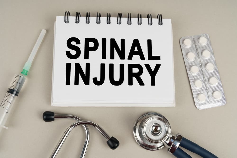 A notepad with "SPINAL INJURY" written on it, surrounded by medical tools, pills, and a syringe.
