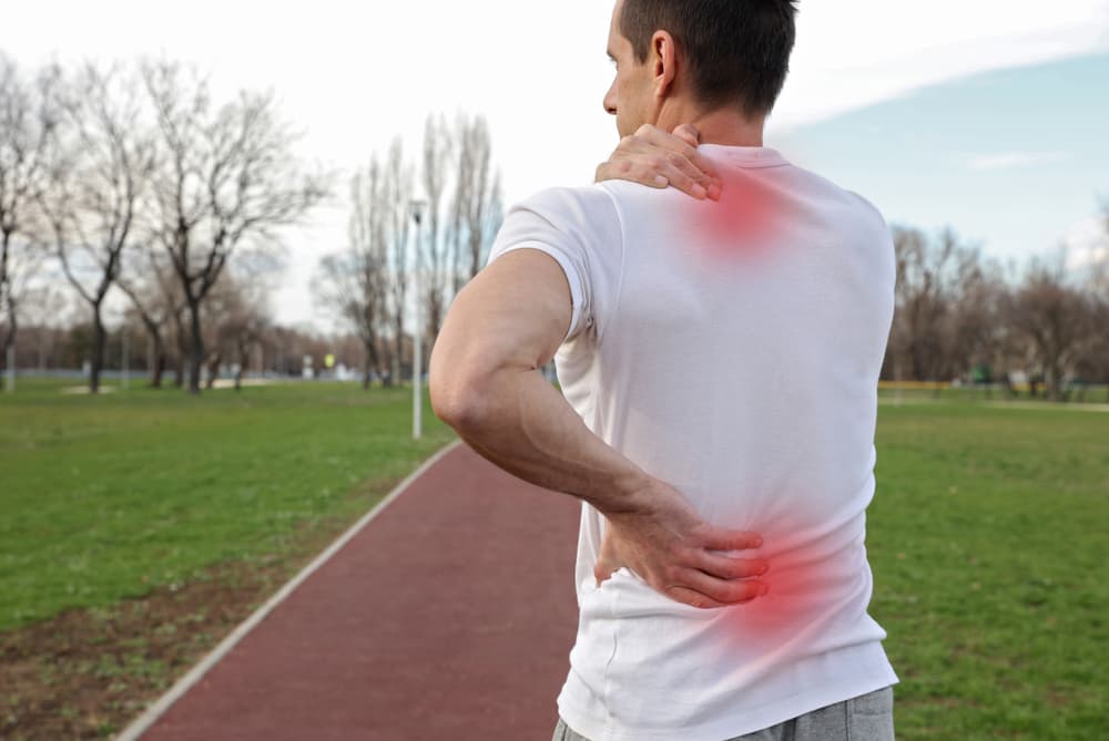 Athlete suffering from spinal cord injury, seeking relief and medical care after a sports injury.