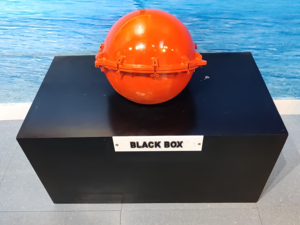 Bright orange truck black box displayed on a pedestal, showcasing crucial crash data recording technology.