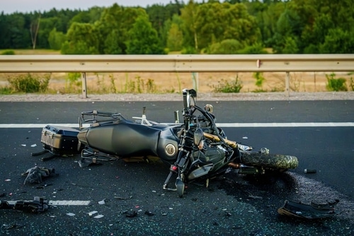 Damaged motorcycle lying on the road after an accident with debris scattered around.