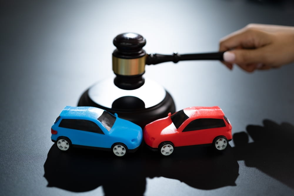 Coches de juguete y mazo de juez que representan reclamaciones de responsabilidad por accidentes de tráfico