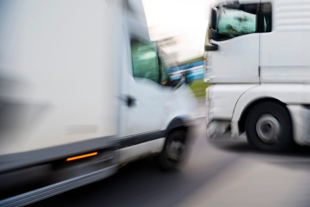 Commercial truck and delivery van narrowly avoiding a collision on the road