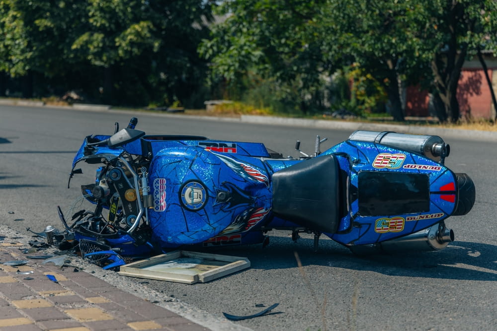 Damaged motorcycle lying on roadway after crash connected to speeding and wide boulevard dangers