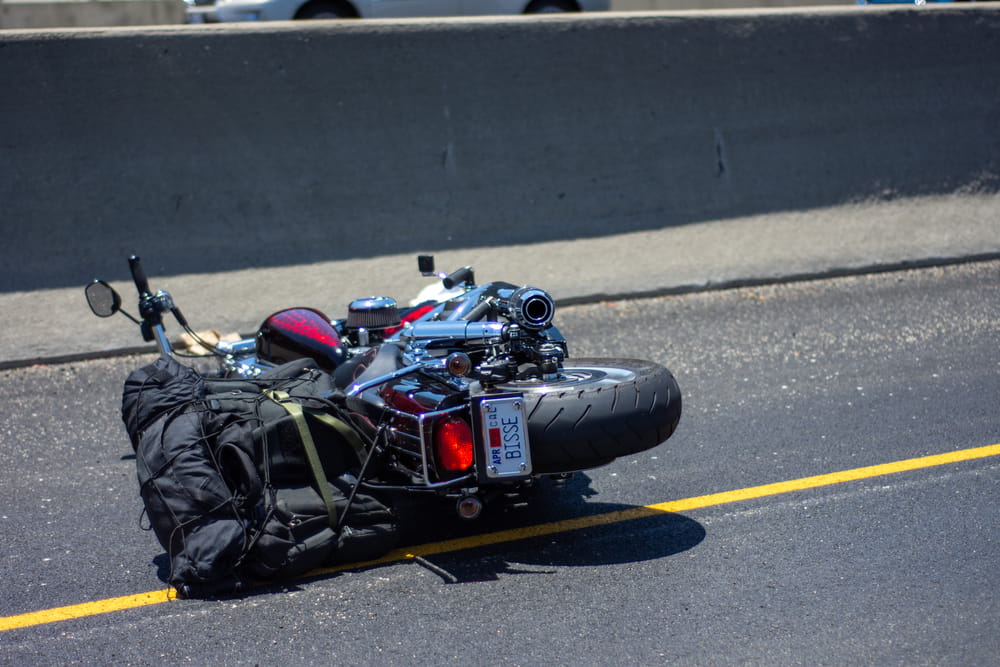 Motorcycle lying on highway pavement after crash connected to coastal road riding hazards