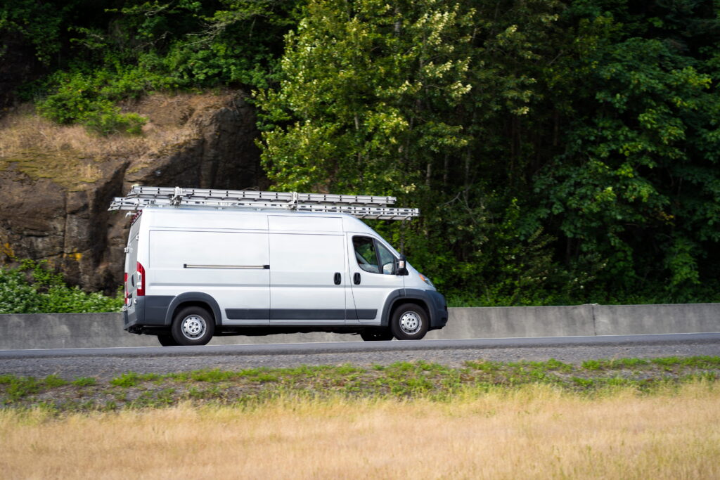 White commercial work van driving through California roadway in employer liability pedestrian accident context