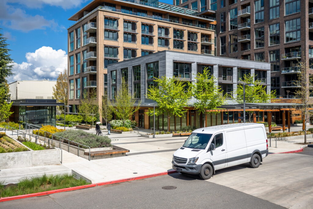Commercial delivery van parked near residential mixed-use buildings where pedestrian accidents may occur