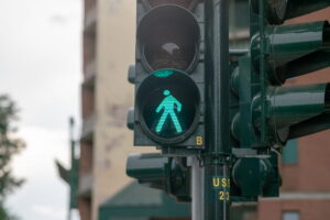 Green pedestrian walk signal at urban intersection near busy San Diego border traffic area