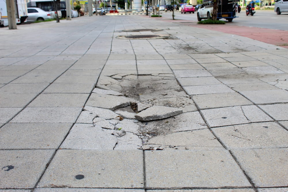 Broken concrete sidewalk and damaged pavement creating a pedestrian trip hazard in Escondido