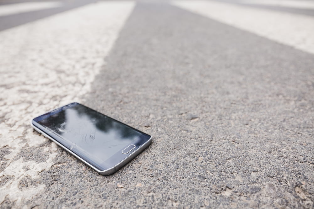 Cell phone lying on the roadway near a pedestrian crosswalk after an accident