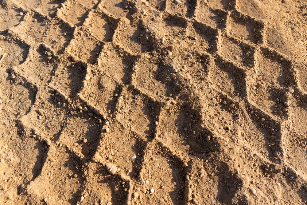 Tire tracks in loose sand illustrating roadway and sidewalk hazards near beach areas