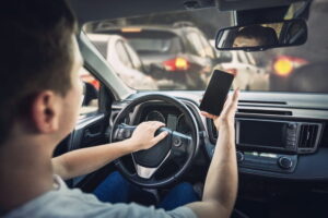 Rideshare driver using a mobile app while driving in traffic during an active Uber or Lyft trip
